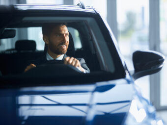 Businessman in suit buying new car at modern salon